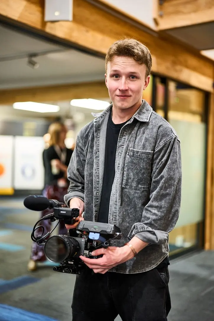 Declan Gale with his FX3 rig between takes, denim shirt, venue foyer behind him