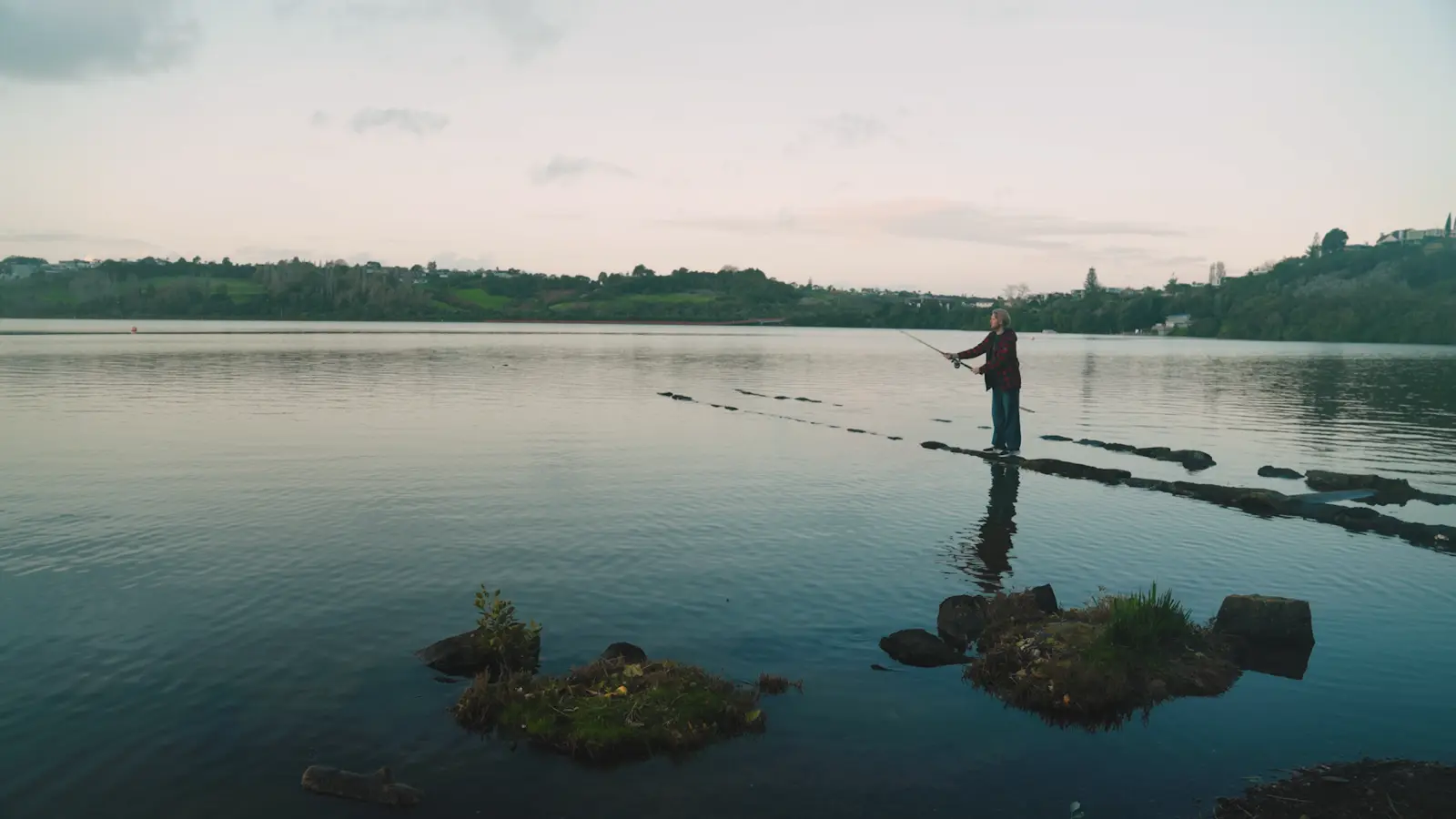 Still from a Declan Gale shoot at Orakei Basin, Auckland: dusk, angler on the causeway